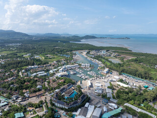 Yacht marina in Phuket, Thailand, located by the sea with scenic views of surrounding mountains. The coastal setting features luxury boats, calm waters, and a tropical landscape.