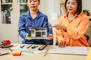 Two female architects discussing an interior design project and drawing blueprints.