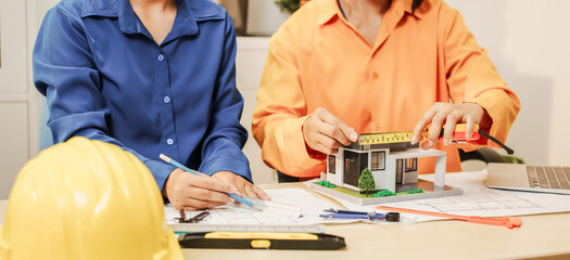 Two female architects discussing an interior design project and drawing blueprints.