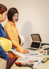 Two female architects discussing an interior design project and drawing blueprints.