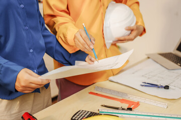 Two female architects discussing an interior design project and drawing blueprints.
