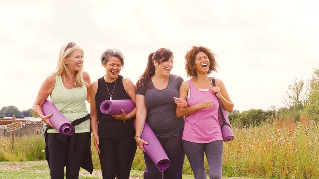 Group Of Mature Female Friends On Outdoor Yoga Retreat Walking Along Path Through Campsite