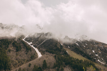 The Caucasus Mountains. The snow-covered peaks are shrouded in thick white clouds.