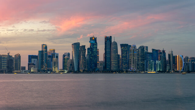 Fototapeta Panorama of Doha, capital of Qatar. View of Doha from the sea. Skyscrapers on a rose and blue background. Modern architecture of Doha at sunset in the evening, view from the sea.