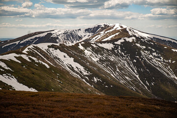 Snow-capped mountains with green slopes under a blue sky during late spring afternoon. Borzhava...