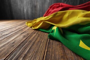 Display of Cameroon flag on wooden surface highlighting national colors and fabric texture