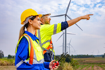 Engineer team man and woman working together with blue print survey plan construction wind turbine...