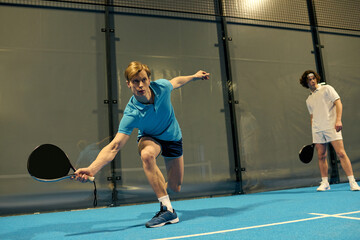 Young sportsmen showcase skills on a padel court during an energetic match