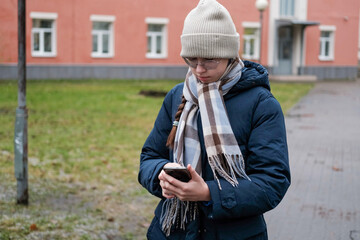 Teenager Girl Walking Alone on City Street with Smartphone. Portrait of 14 years old girl wearing...