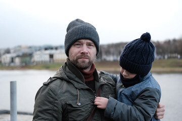 Father and son walking down on sidewalk together. Portrait of a handsome middle-aged man with...