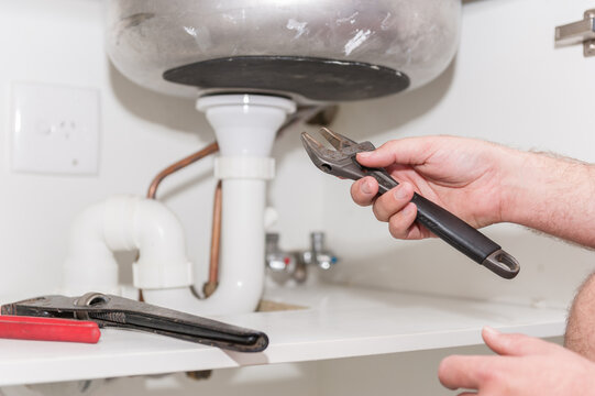 Plumber installing a sink and pipes with spanner