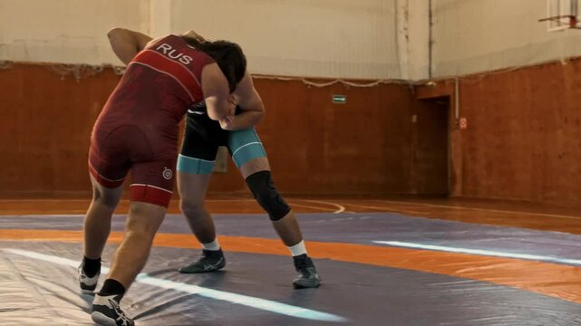 two freestyle wrestlers fight in clinch on tatami