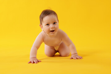 Cute little baby crawling on yellow background