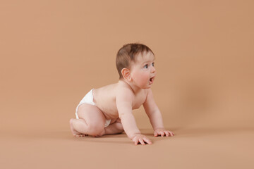 Cute little baby crawling on beige background