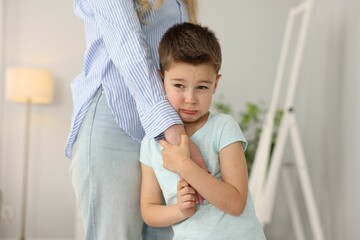 Little boy afraid to leave without mother and holding hands with her at home. Separation anxiety