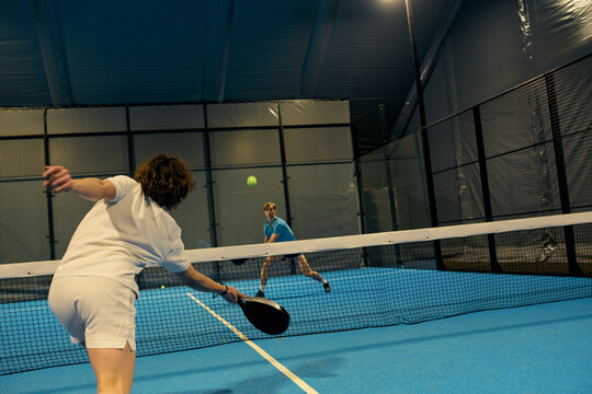Exciting match between young padel players on a vibrant indoor court