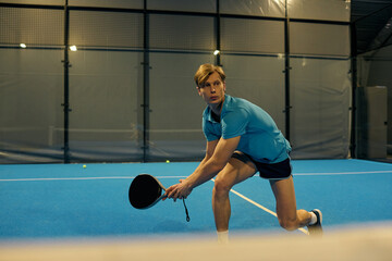 Young sportsman showcasing skills in padel match on vibrant indoor court