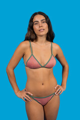 Naklejka premium Confident young woman posing in bikini on blue background