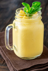 Chilled mango lassi in mason jar topped with mint and mango cubes