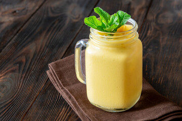 Chilled mango lassi in mason jar topped with mint and mango cubes