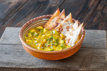 Fresh mango salsa served with tortilla chips in rustic wooden food setting