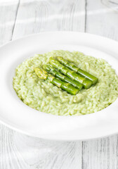 Asparagus risotto served in white plate with whole spears on top