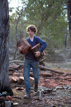 Young man carrying logs for firewood