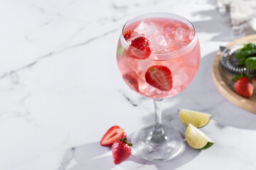 Strawberry gin tonic cocktail on white marble background. Copy space