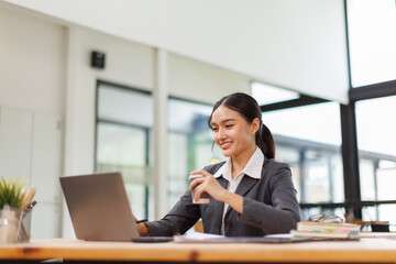 Asian business woman accounting holding coffee cup using calculating income-expenditure and...