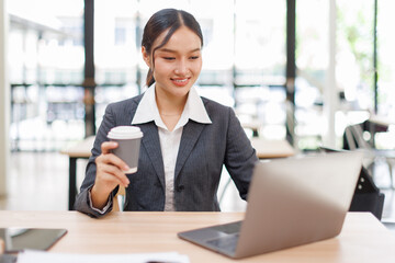Asian business woman accounting holding coffee cup using calculating income-expenditure and...