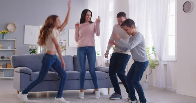 Happy family joy, couple dancing with little children in modern warm living room, moving new home after successful bank loan and lending, enjoy fun with kids, active leisure amusement, celebrating