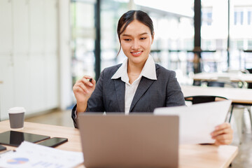 Attractive asian young confident businesswoman Accounting using calculating income-expenditure and...