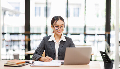 Attractive asian young confident businesswoman Accounting using calculating income-expenditure and...