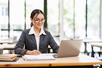 Attractive asian young confident businesswoman Accounting using calculating income-expenditure and...