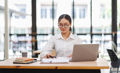 Attractive asian young confident businesswoman Accounting using calculating income-expenditure and...
