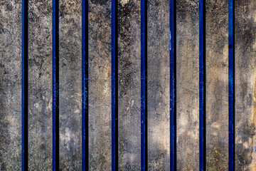 Textured concrete wall with vertical blue stripes and weathered surface