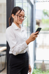 Fototapeta premium Asian business woman use cellphone and smile in the office 