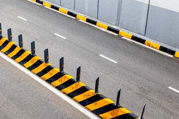 Urban road divider with yellow and black safety barriers on asphalt