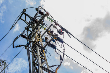 Electric power lines against blue sky with clouds