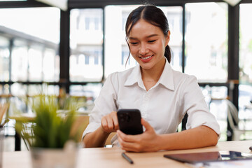 Young asian woman using phone at work desk. Using online connect technology for business, education...