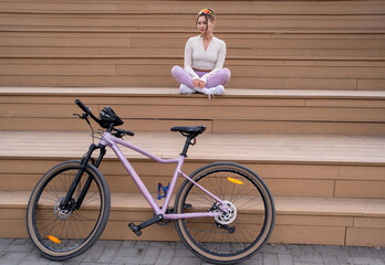 A Trendy Woman Dressed in Stylish Activewear is Enjoying a Relaxing Moment by Her Bicycle