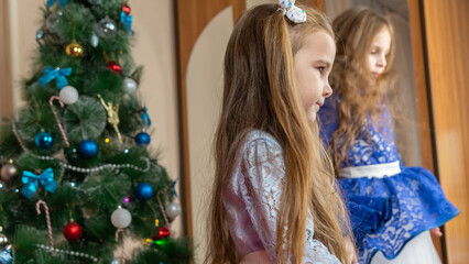 Little girls in festive dress dancing near christmas tree at home
