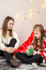 Happy mother and daughter opening christmas gift at home