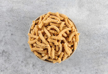 Indian snack murukku made from rice flour and spices on grey background. Top view. Indian food.