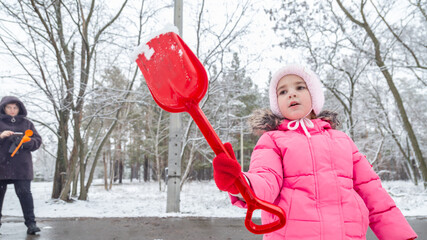 Little girl playing in a snowy park in winter