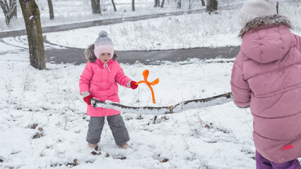 Active recreation with children in winter on cold days. Happy siblings having fun with snow