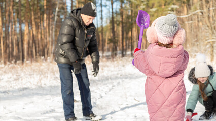 Playful family enjoying snowball fight in snowy winter park
