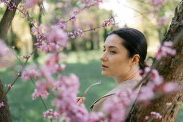 a woman dressed in a spring jacket, pants and sunglasses poses exquisitely against the background...