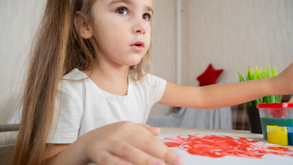Child girl playing with digital wireless tablet computer on bed at home.