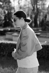 a woman dressed in a spring jacket, pants and sunglasses poses for a photo while walking in the...